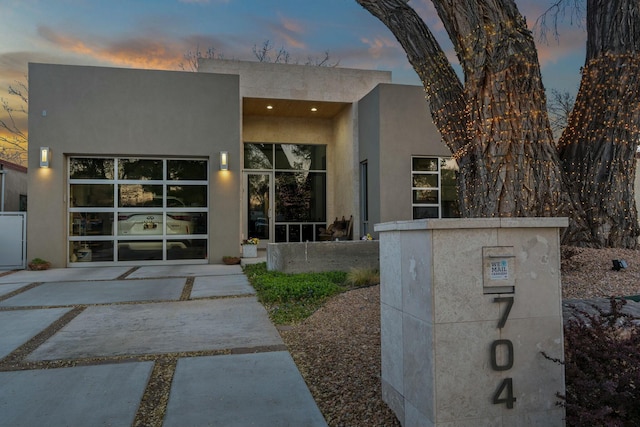 exterior entry at dusk featuring stucco siding