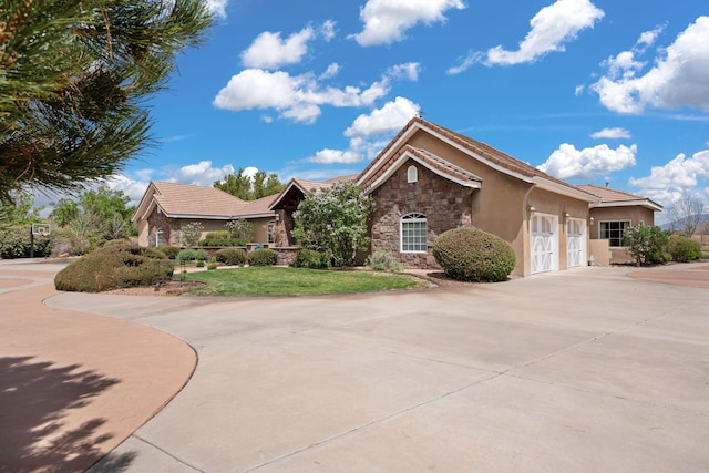 single story home with a tile roof, driveway, stone siding, a garage, and stucco siding