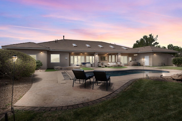 rear view of house with a tile roof, a patio area, an outdoor pool, stucco siding, and an outdoor living space