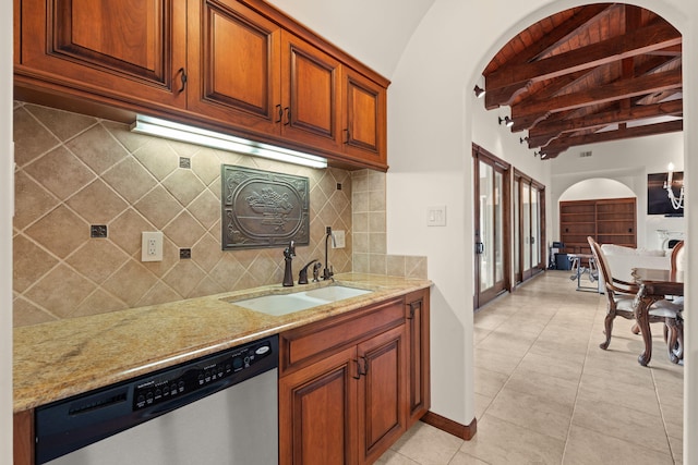 kitchen with backsplash, dishwasher, a sink, light stone countertops, and lofted ceiling with beams
