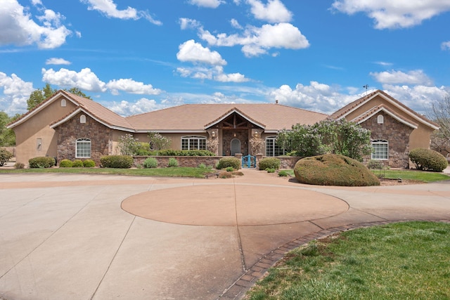 ranch-style home featuring stone siding, a tiled roof, and stucco siding