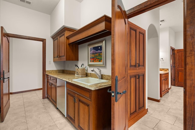 kitchen featuring light stone countertops, visible vents, a sink, and light tile patterned floors