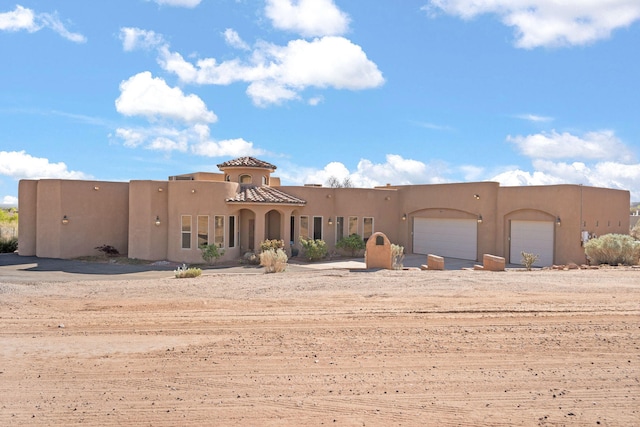 5720 Rio Lama Rd NE, Rio Rancho, NM 87144 - pueblo-style home with driveway, a garage, and stucco siding