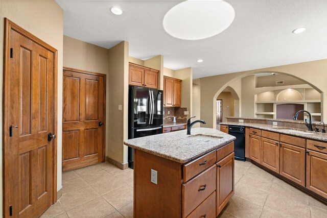 5720 Rio Lama Rd NE, Rio Rancho, NM 87144 - kitchen with black appliances, light stone counters, an island with sink, and a sink