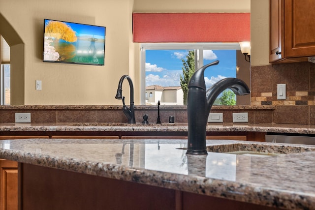 5720 Rio Lama Rd NE, Rio Rancho, NM 87144 - kitchen featuring brown cabinets, decorative backsplash, and light stone counters