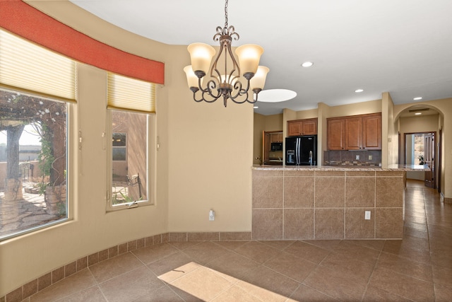 5720 Rio Lama Rd NE, Rio Rancho, NM 87144 - kitchen with arched walkways, an inviting chandelier, brown cabinetry, decorative light fixtures, and black appliances