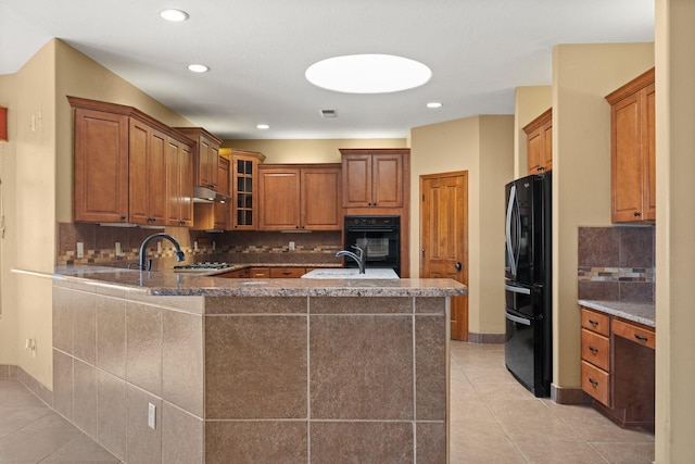 5720 Rio Lama Rd NE, Rio Rancho, NM 87144 - kitchen featuring light tile patterned floors, glass insert cabinets, black appliances, a peninsula, and backsplash