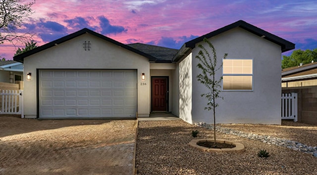 ranch-style home with stucco siding, fence, decorative driveway, and a garage