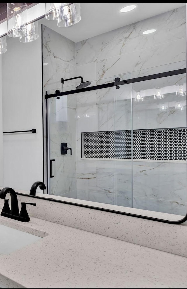 bathroom with a marble finish shower and a sink
