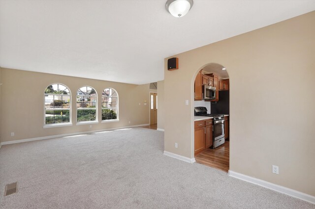 10516 Calle Sombra NW, Albuquerque, NM 87114 - unfurnished living room featuring arched walkways, visible vents, baseboards, and light carpet