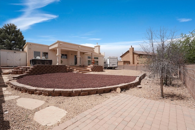 10516 Calle Sombra NW, Albuquerque, NM 87114 - exterior space with a storage unit, a fenced backyard, a patio area, an outdoor structure, and stucco siding