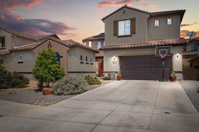 mediterranean / spanish house featuring stucco siding, a tiled roof, and concrete driveway