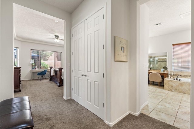 corridor with baseboards, a textured ceiling, and carpet floors