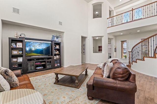 living room with baseboards, stairs, wood finished floors, and visible vents