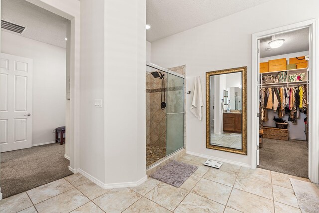 4024 Colina Roja Ln NE, Rio Rancho, NM 87124 - full bath with a shower stall, a textured ceiling, a walk in closet, tile patterned floors, and baseboards
