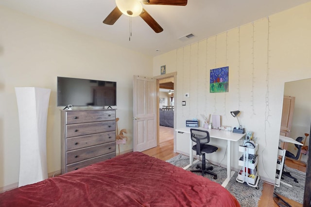 bedroom with a ceiling fan, visible vents, and wood finished floors