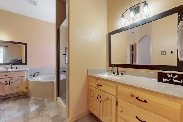 full bathroom featuring a sink, two vanities, a garden tub, and visible vents