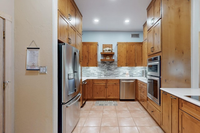 kitchen with appliances with stainless steel finishes, a sink, light countertops, tasteful backsplash, and visible vents