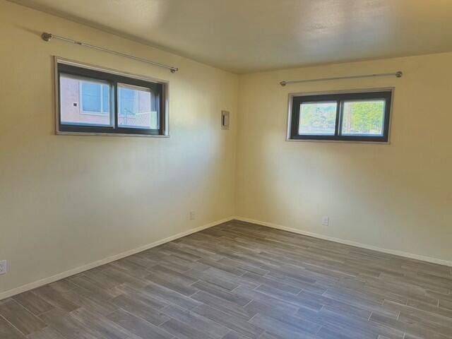 spare room with baseboards and wood finished floors