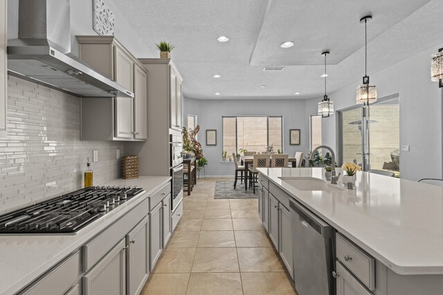 12209 Bear Valley Ln NW, Albuquerque, NM 87120 - kitchen featuring wall chimney range hood, a textured ceiling, a sink, stainless steel appliances, and gray cabinetry