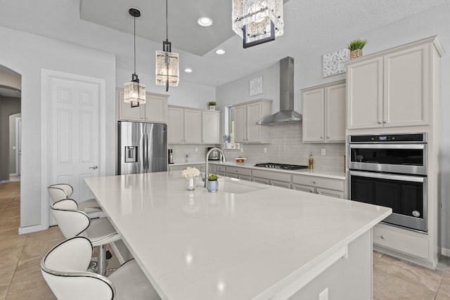 12209 Bear Valley Ln NW, Albuquerque, NM 87120 - kitchen featuring stainless steel appliances, a sink, arched walkways, wall chimney exhaust hood, and decorative backsplash