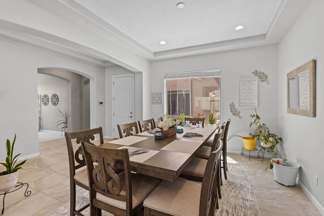 12209 Bear Valley Ln NW, Albuquerque, NM 87120 - dining area with light tile patterned floors, arched walkways, a raised ceiling, baseboards, and recessed lighting
