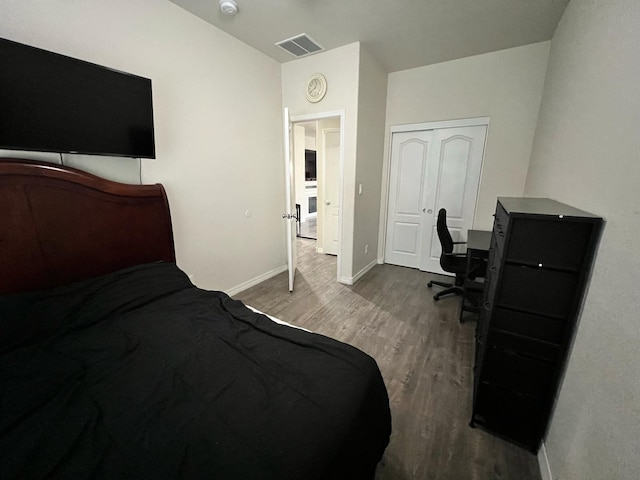 bedroom with a closet, visible vents, wood finished floors, and baseboards