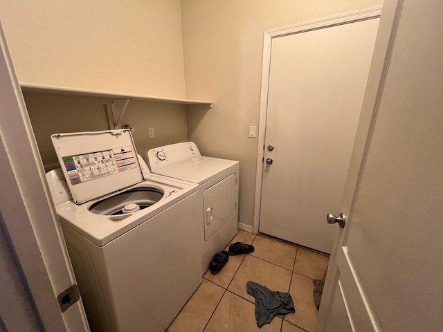 clothes washing area featuring light tile patterned floors, washing machine and dryer, and laundry area