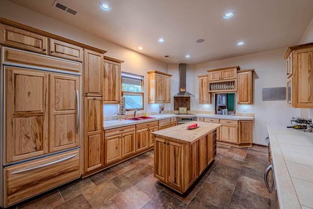 6 Storyteller Ct, Sandia Park, NM 87047 - kitchen with paneled refrigerator, wall chimney range hood, butcher block counters, recessed lighting, and a center island