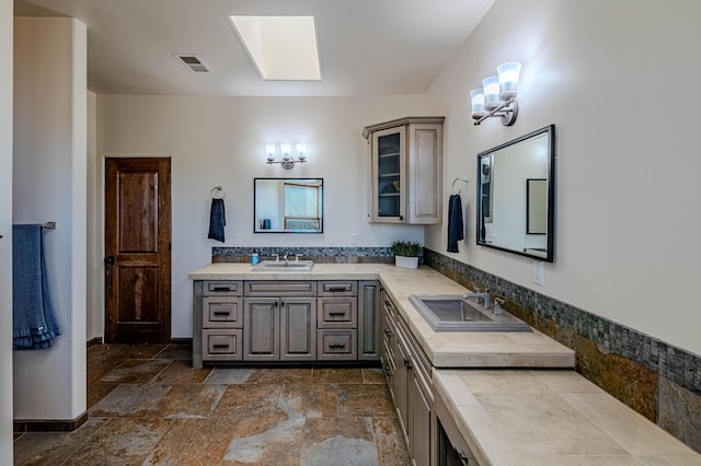 6 Storyteller Ct, Sandia Park, NM 87047 - full bathroom featuring double vanity, a skylight, and stone finish flooring