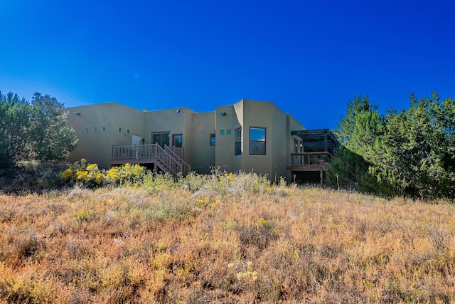 6 Storyteller Ct, Sandia Park, NM 87047 - back of property with stucco siding and a wooden deck