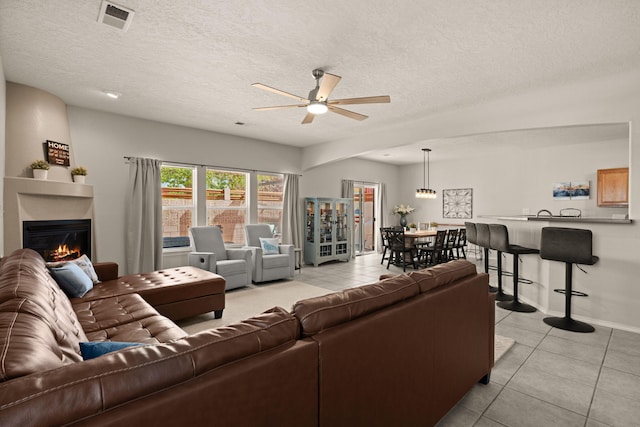 4201 High Mesa Rd SE, Rio Rancho, NM 87124 - living area featuring ceiling fan, light tile patterned floors, a glass covered fireplace, a textured ceiling, and baseboards