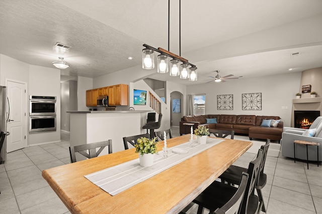 4201 High Mesa Rd SE, Rio Rancho, NM 87124 - dining room with light tile patterned flooring, ceiling fan, a warm lit fireplace, and arched walkways