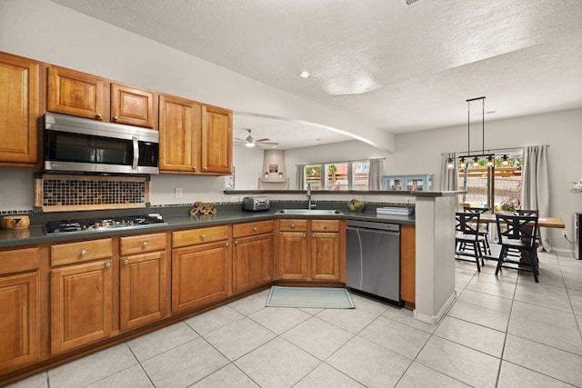 4201 High Mesa Rd SE, Rio Rancho, NM 87124 - kitchen featuring stainless steel appliances, a sink, brown cabinets, and a textured ceiling