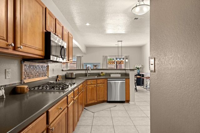 4201 High Mesa Rd SE, Rio Rancho, NM 87124 - kitchen featuring stainless steel appliances, a sink, a textured wall, dark countertops, and a peninsula