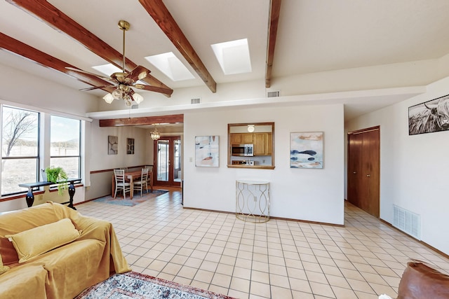 living room featuring light tile patterned flooring, a skylight, visible vents, and beam ceiling