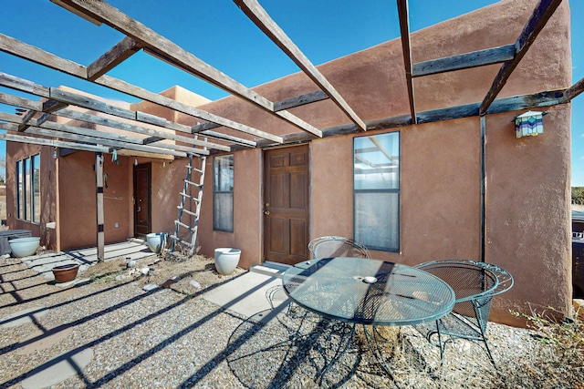 rear view of property featuring a pergola, a patio area, and stucco siding