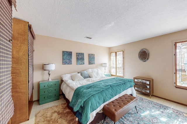tiled bedroom featuring a textured ceiling and visible vents