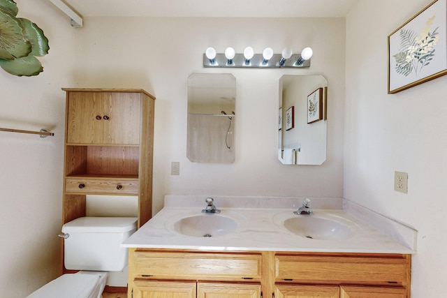 bathroom featuring double vanity, a sink, and toilet
