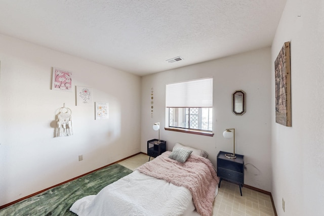 bedroom with baseboards, a textured ceiling, and visible vents