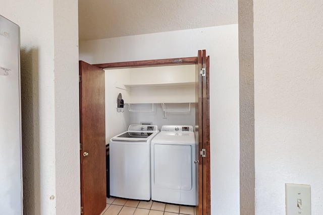 washroom with light tile patterned floors, separate washer and dryer, a textured wall, and laundry area