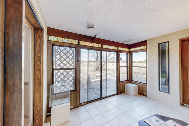 unfurnished sunroom featuring a textured ceiling and tile patterned floors
