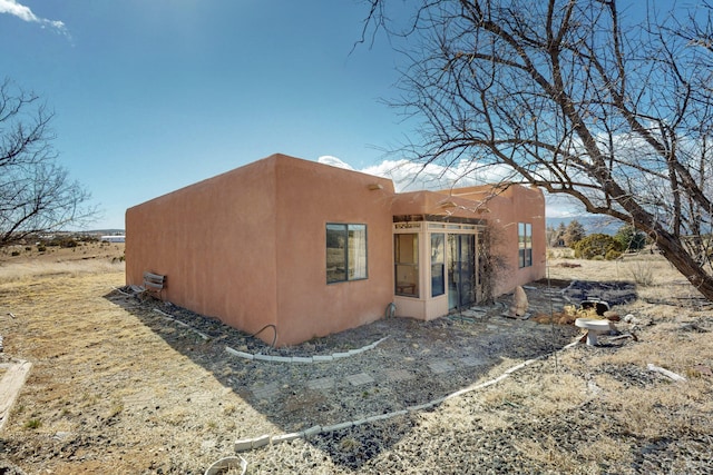 back of property with a sunroom and stucco siding