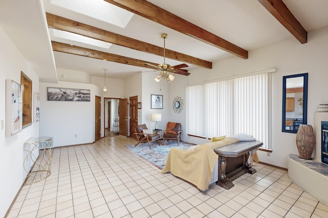 living area with ceiling fan, beamed ceiling, and light tile patterned flooring