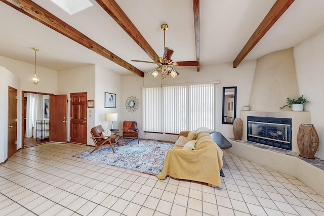 living area featuring a fireplace, a ceiling fan, beam ceiling, and light tile patterned flooring