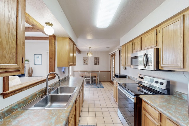 kitchen with light brown cabinetry, a sink, light countertops, stainless steel appliances, and light tile patterned floors