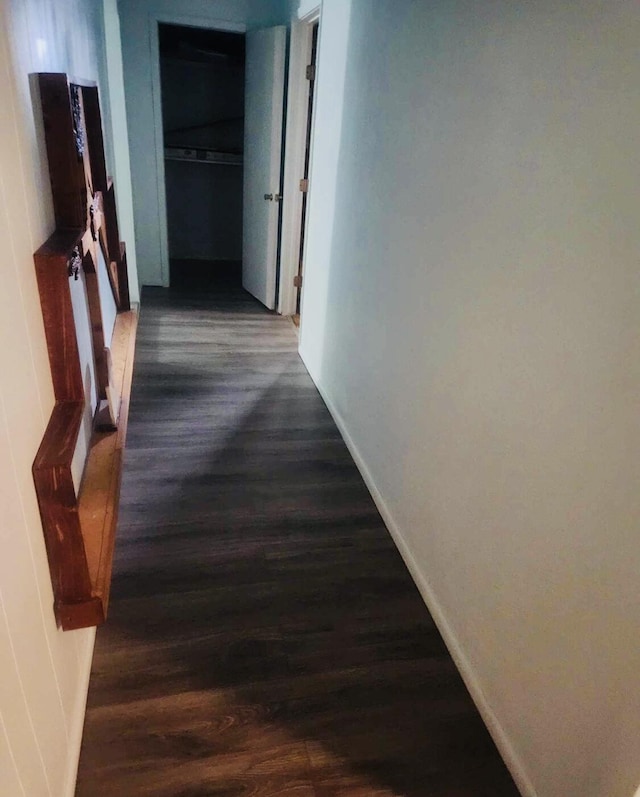 corridor featuring dark wood-type flooring and baseboards