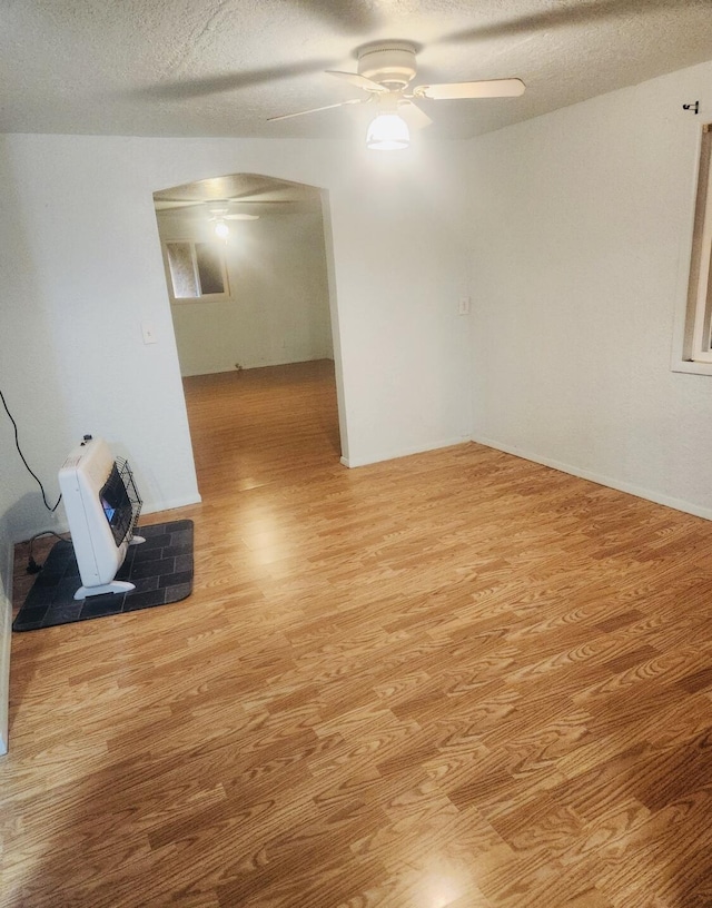 spare room with heating unit, a textured ceiling, ceiling fan, and wood finished floors