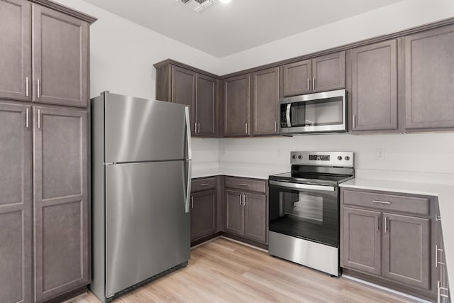 2507 Calle Del Los Claveles, Belen, NM 87002 - kitchen featuring stainless steel appliances, light countertops, light wood-style flooring, and dark brown cabinets