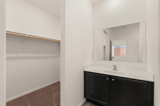 bathroom with vanity, baseboards, and a walk in closet